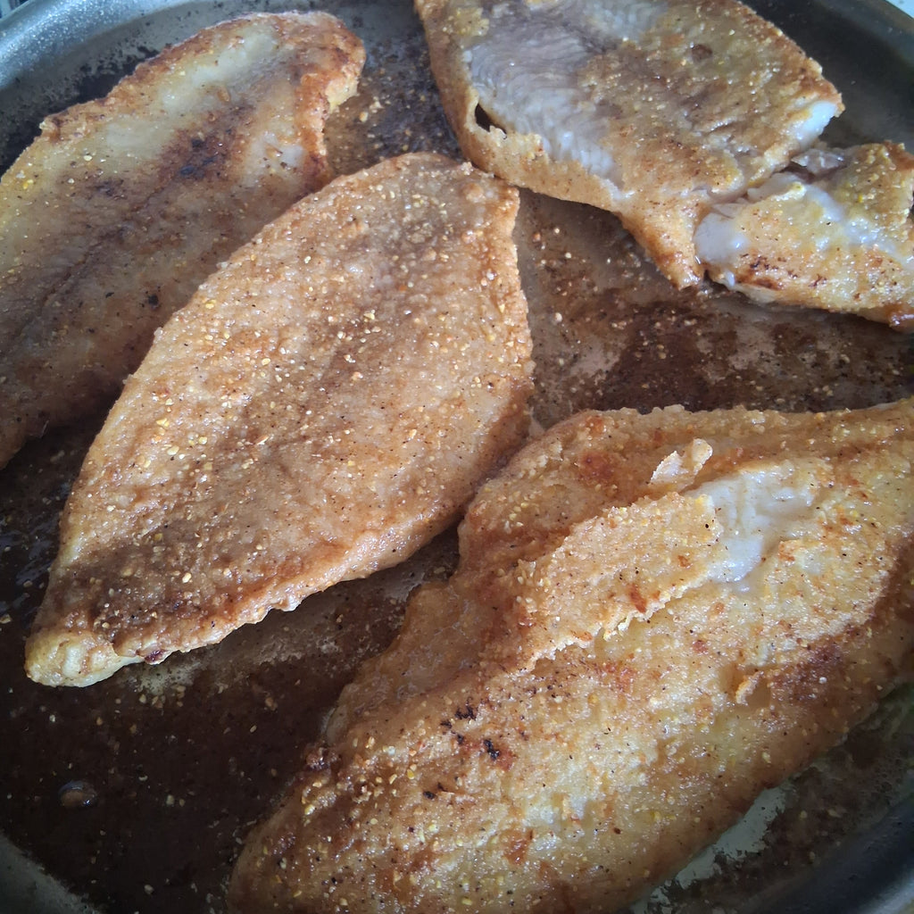 Fried fish fillets in a pan on a stove