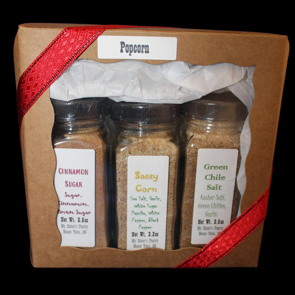 Three spice jars in a cardboard box with a red ribbon on a dark background